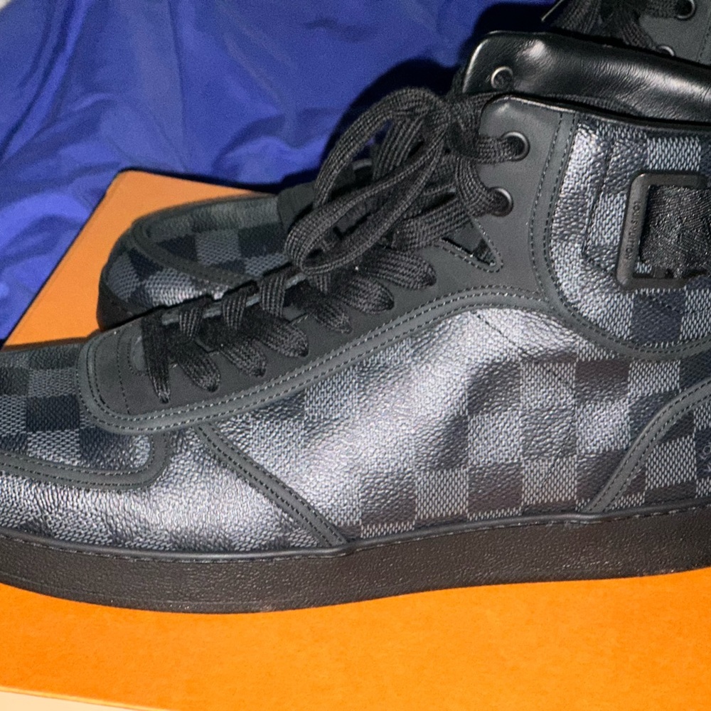 The Rivoli sneaker boot is a sleek hi-top in LV iconic Damier Graphite canvas.